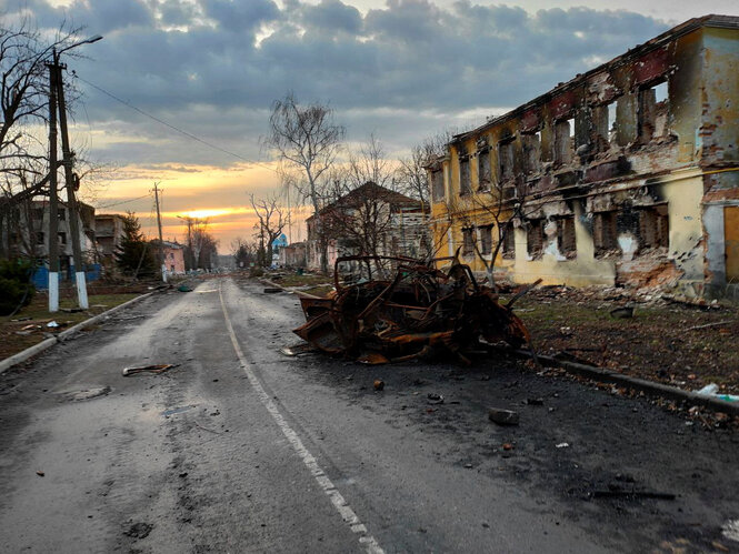 Ein total ausgebranntes Fahrzeug in einer vom Krieg zerstörten Straße in Sudcha