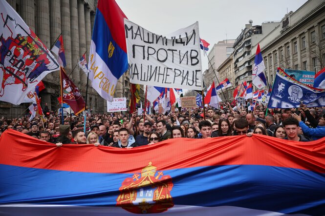 Demonstranten marschieren während einer Großkundgebung in Belgrad und halten serbische Flaggen in die Höhe