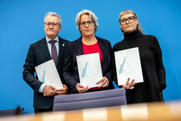Drei Menschen stehen nebeneinander und halten ein Papier hoch
