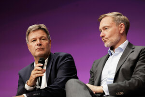 Zu sehen ist Bundeswirtschaftsminister Robert Habeck mit einem mikrofon in der Hand, sprechend. Neben ihm sitzt Christian Lindner und zieht eine Schnute.