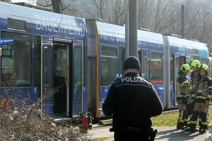 Einsatzkräfte von Polizei und Feuerwehr stehen vor der Straßenbahn in Gera, in der die Frau angezündet wurde