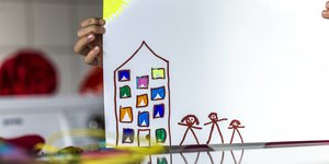 Eine Kinderbild zeigt ein Haus mit Menschen davor.
