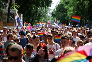 Fröhliche Menschen mit Regenbogenflaggen bei der letzten Pride Parade