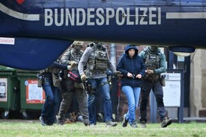 Hinter einem Helikopter mit der Aufschrift Bundespolizei wird eine Frau in Handschellen von Polizisten abgeführt