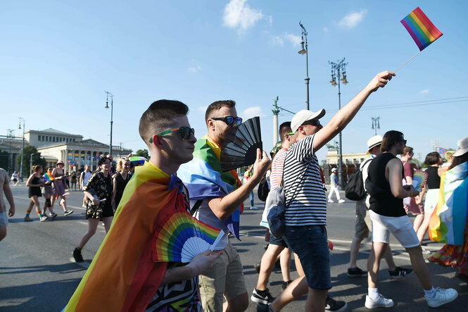 Mehrer personen bei einem Pride March mit Regenbogenfahne.