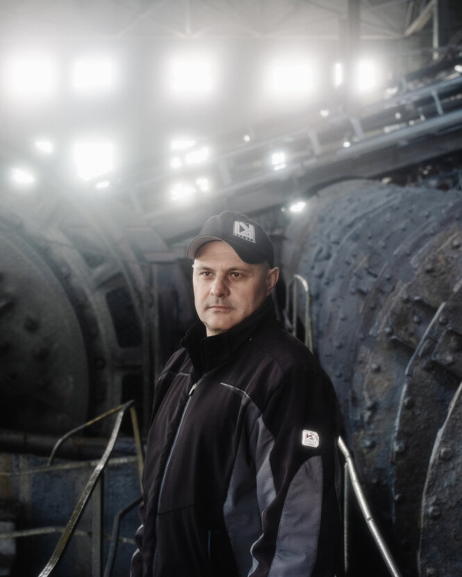 Ein Mann mit Basecap und schwarzer Jacke steht in einer Industriehalle