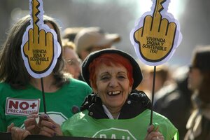 Deomonstration gegen Wohnungsnot, eine Frau in grünem T-Shirt und roten Haaren lacht, sie tragt einen Stinkefinger aus Pappe mit der Forderung: Menschenwürdiger und nachhaltiger Wohnraum Jetzt!