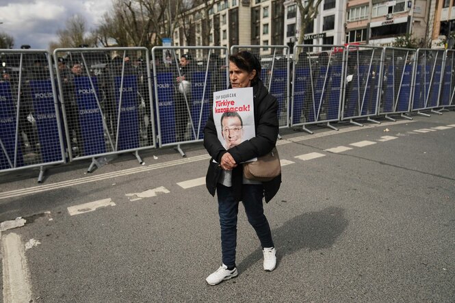 Frau mit Plakat vor Polizreiabsperrung