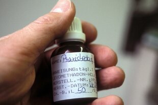 Eine Hand hält eine kleine Flasche mit Methadon