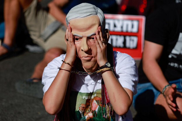 Eine Person in Handschellen und mit Netanjahu-Maske protestiert bei einer Kundgebung gegen den israelischen Premierminister Benjamin Netanjahu und seine Regierung