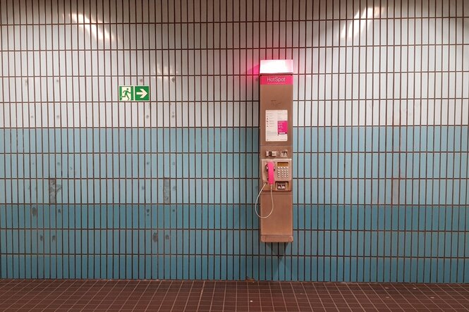 Eine Telefonstele der Telekom vor der Fliesenwand in einem U-Bahnhof