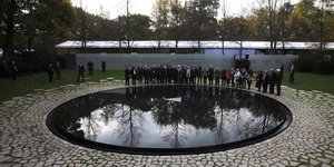 Menschen stehen an der Sinti-und-Roma-Gedenkstätte in Berlin
