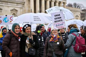 Ältere Frauen demonstrieren mit Regenschirmen und Schildern, darauf steht 