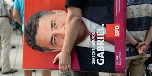 Ein Wahlhelfer trägt ein Wahlplakat von Sigmar Gabriel