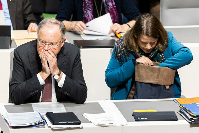 Kultusministerin Julia Willie Hamburg (Grüne) sitzt neben Ministerpräsident Stephan Weil (SPD) im Landtag auf der Regierungsbank und wühlt in ihrer Tasche.