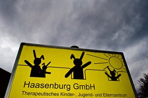 Ein gelbes Schild mit drei schwarzen Hasen vor grauen Wolken