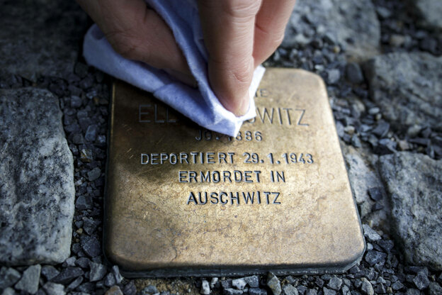 Eine Person putzt einen Stolperstein, der an die Verfolgte des Nationalsozialismus und in Auschwitz ermordete Ella Horowitz erinnert