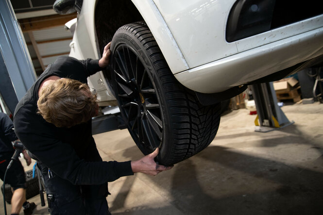 Autowerkstatt, ein Mensch hantiert an einem Reifen