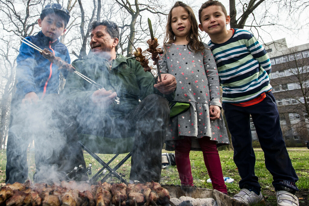 Ein älterer Herr grillt mit seinen Enkeln in einem Park in Berlin