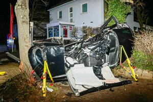 Das völlig zerstörtes Autowrack zwischen Bäumen am Straßenrand