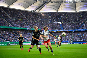 zwei Fußballerinnen kämpfen im vollbesetzten Volksparkstadion um den Ball