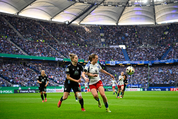 zwei Fußballerinnen kämpfen im vollbesetzten Volksparkstadion um den Ball