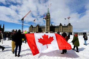 Menschen halten eine große kanadische Flagge während einer Kundgebung als Reaktion auf die Drohungen von US-Präsident Donald Trump gegen die kanadische Souveränität auf dem Parliament Hill in Ottawa