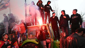 Demonstranten stehen auf einem Traktor und brennen Pyrotechnik ab