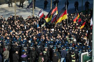 Teilnehmer einer rechtsextremistischen Demonstration mit Deutschlandfahnen und Polizisten stehen sich am S-Bahnhof Ostkreuz gegenüber