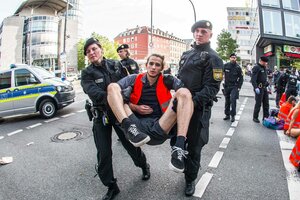 Eine Person wird bei einer Straßenblockade von Polizisten weggetragen.