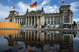 Passanten gehen bei sonnigem Wetter an dem Reichstagsgebäude vorbei.