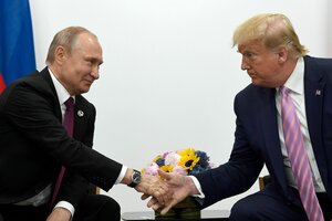 Putin und Trump schütteln sich, jeweils auf Stühlen sitzend, die Hände