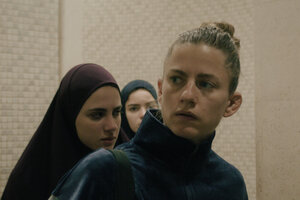 Sarah (Florentina Holzinger) mit zwei jungen Frauen mit Hidschab in einem anonymen Gebäude.