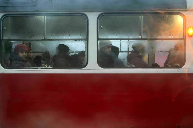Menschen sitzen in einem roten Bus und blicken aus verregneten Fensterscheiben