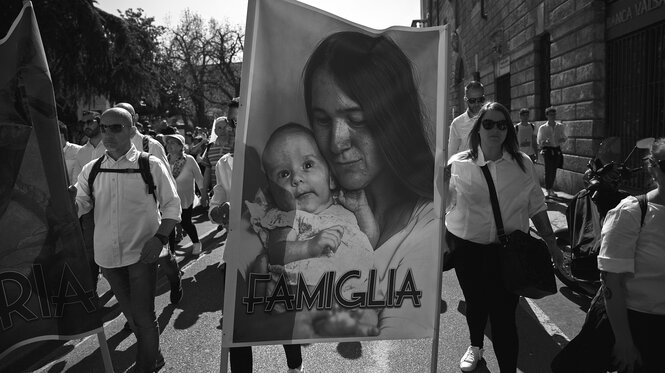 Menschen demonstrieren mit einem Plakat, das eine Mutter mit ihrem Baby zeigt