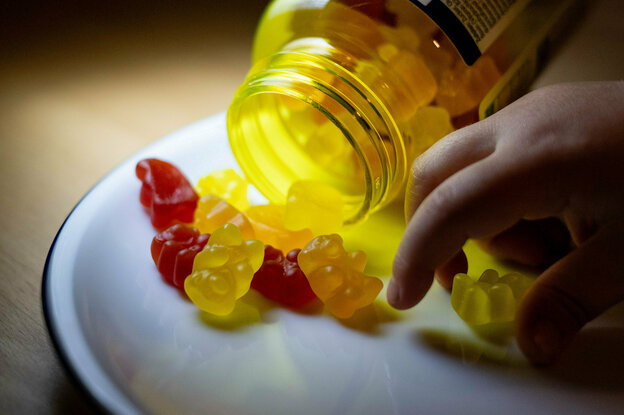 Ein Kind nimmt sich ein Kinder-Vitaminbärchen von einem Teller