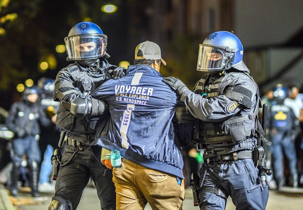 Ein Mann, der zu einer Gruppe von Menschen gehört, die nach Ausschreitungen bei einer Eritrea-Veranstaltung von Polizeikräften eingekesselt wurden, wird von Polizisten abgeführt