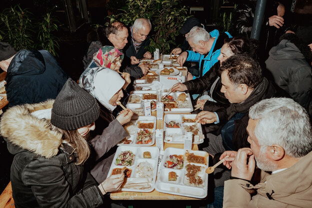 Menschen sitzen an Tischen und essen.
