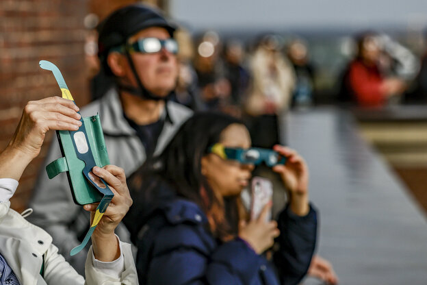 Besucher des Hamburger Planetariums betrachten von der Aussichtsterasse aus mit Schutzbrillen eine partielle Sonnenfinsternis.