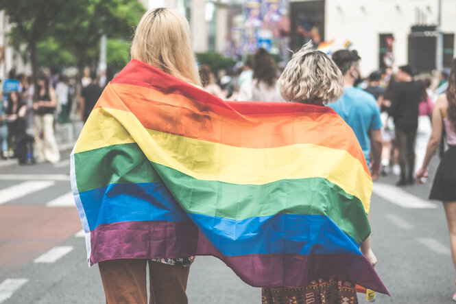 Zwei junge Menschen von hinten mit LGBTQ-Fahne in Bukarest