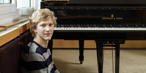 Portraitaufnahme des jungen blonden Musikers Jan Liesicki vor einem Steinway-Konzertflügel