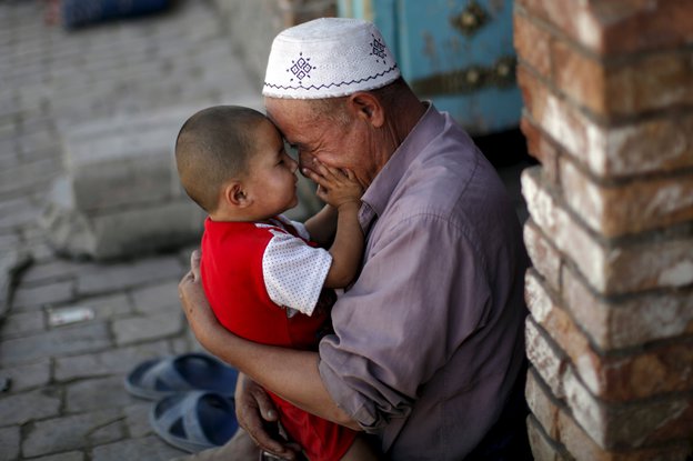 Ein alrer chinesischer Mann knuddelt seinen Enkel