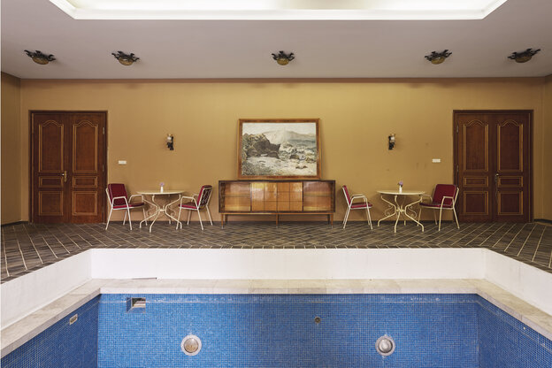 Ein leerer In-door-Swimmingpool, im Hintergrund eine Sitzecke