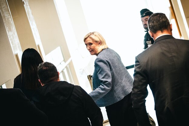 Marine le Pen dreht sich um, mehrere Männer folgen ihr