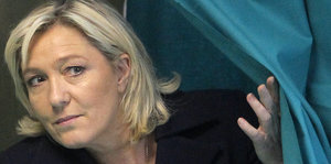 Marine Le Pen schiebt den Vorhang einer Wahlkabine zur Seite
