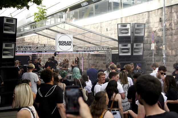 Rave Atmosphäre; über der tanzenden Menge hängt ein Schild des Boiler Rooms