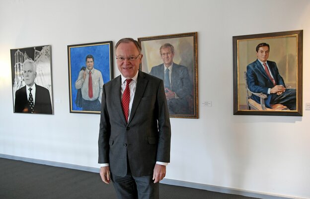 Stephan Weil steht vor einer Gemälde und Fotogalerie seiner Vorgänger