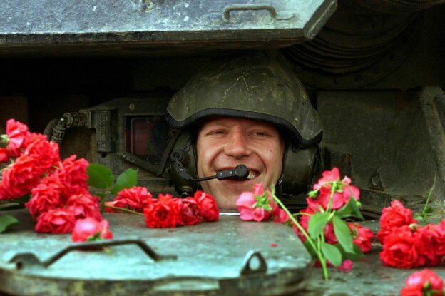 Ein lächelnder Fahrer schaut aus seinem mit Rosen bedeckten Panzer.