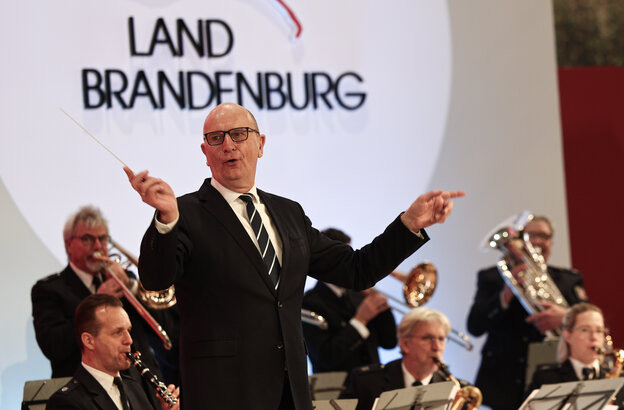 Das Foto zeigt den brandenburgischen Ministerpräsidenten Dietmar Woidke (SPD) beim Dirigieren des Landespolizeiorchesters