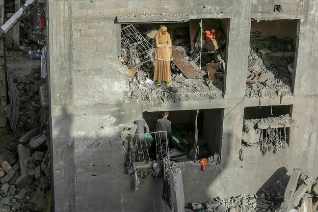 Menschen stehen in einem ausgebombten Haus